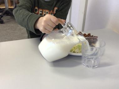 Barn hælder mælk op i glas